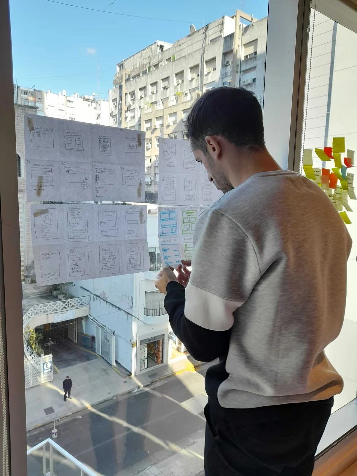 Maxi Cris revisando bocetos de interfaces junto a una ventana